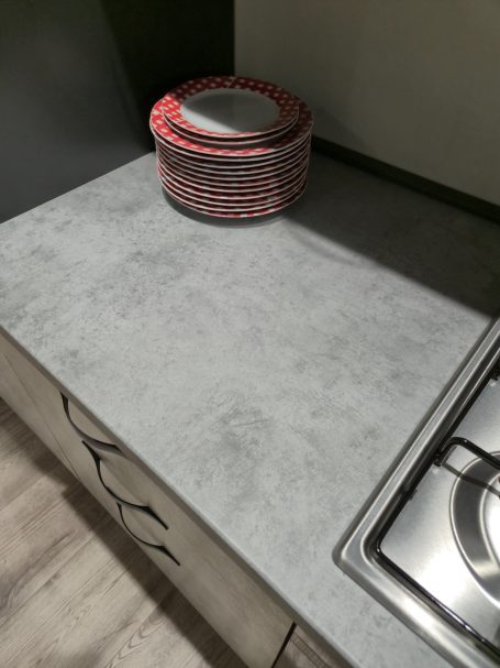 Grijze keukenblad met een stapel rode en witte pannen en een kookplaat.