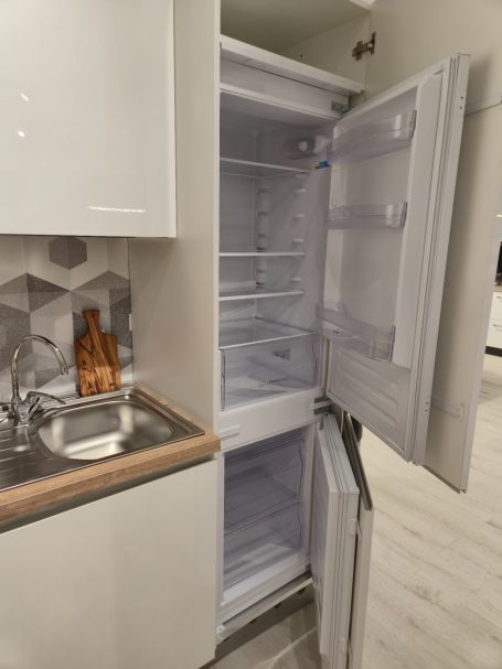 Pure elegantie in Italiaans design Lege koelkast met open deuren, naast een keukenblad en gootsteen.