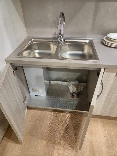Tijdloze elegantie met Italiaans design Dubbele spoelbak met onderkast en zichtbare leidingen in een moderne keuken.