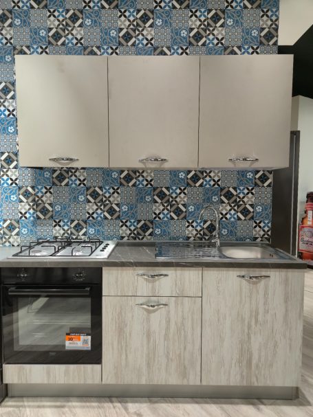 Moderne keuken met gasfornuis, oven en wand met blauw-witte tegels.