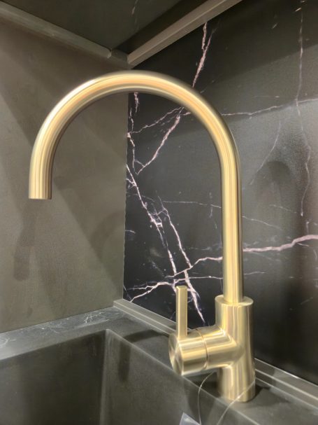 Moderne antracietgrijze keuken Gouden keukenkraan met hoge, gebogen uitloop bij een spoelbak.