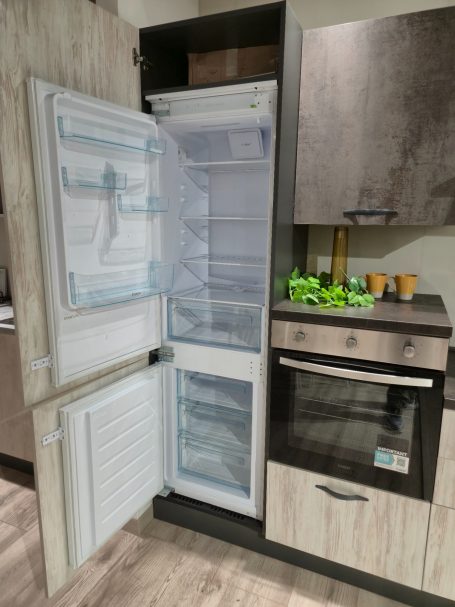 Open koelkast met nul graden compartiment en een oven ernaast. Groenten staan op de aanrecht.