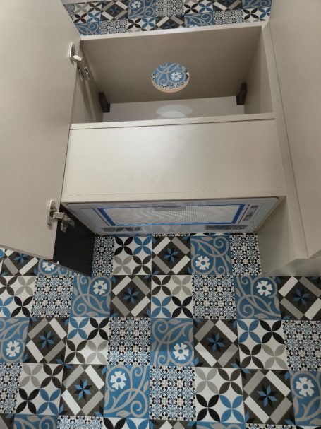 Open kast met een laden en een betegelde vloer in blauw en grijs.