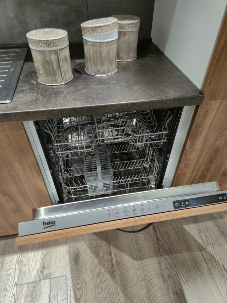 Warme uitstraling, slim ontworpen Een open vaatwasser in een keukenkast, met twee blikken bovenop.