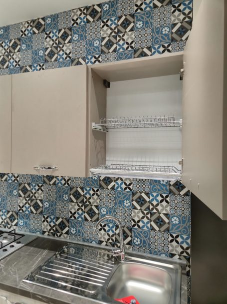 Moderne keuken met blauwgekleurde tegels en open kast zonder inhoud.
