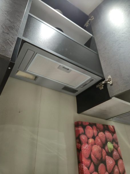 Lade in een moderne keuken met een afzuigkap en een muurdecoratie van aardbeien.