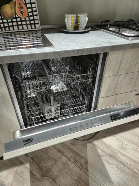 Een open vaatwasser in een moderne keuken met aanrecht en een bord bovenop.