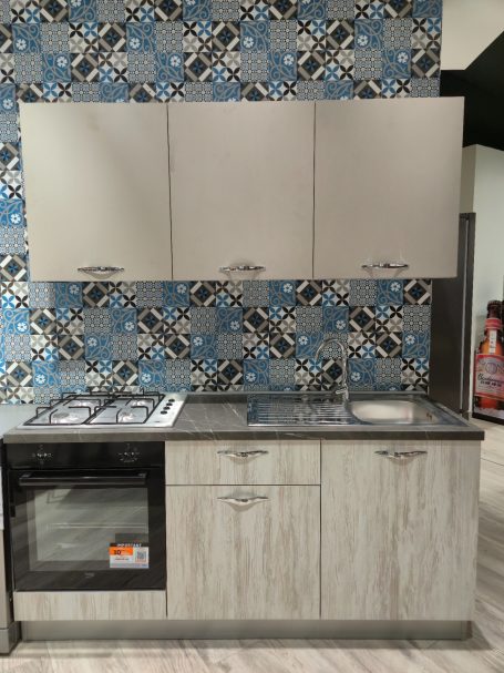 Moderne keuken met een fornuis, een gootsteen en een betegelde muur in blauw en wit.