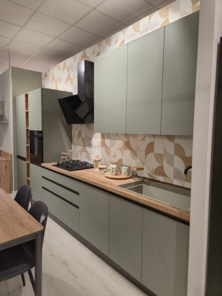 Moderne matgroene keuken Moderne keuken met groene kasten, een stenen werkblad en een betegelde achterwand.