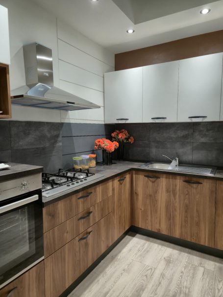 Warme uitstraling, slim ontworpen Moderne keuken met houten kasten, een gasfornuis en een afzuigkap.