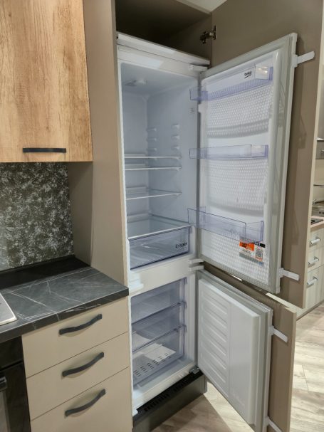 Modern design met een stijlvolle twist Een lege koelkast met een vriesgedeelte en een moderne kast ernaast.