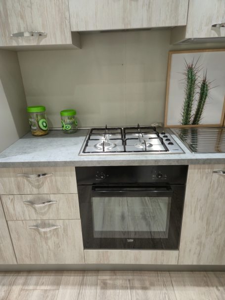 Moderne keuken met een gasfornuis, oven en groene kruidenpotten.