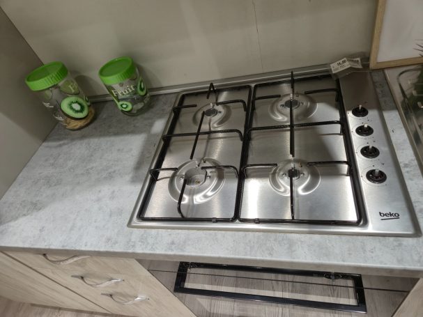 Gaskookplaat met vier branders op een lichte aanrecht. Twee groene potten op de achtergrond.