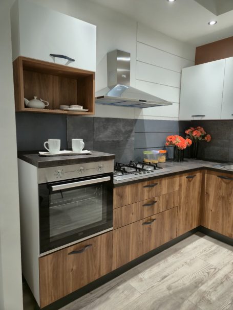 Warme uitstraling, slim ontworpen Moderne keuken met een oven, kookplaat en een houten kast met servies. Oranje bloemen decoreren.