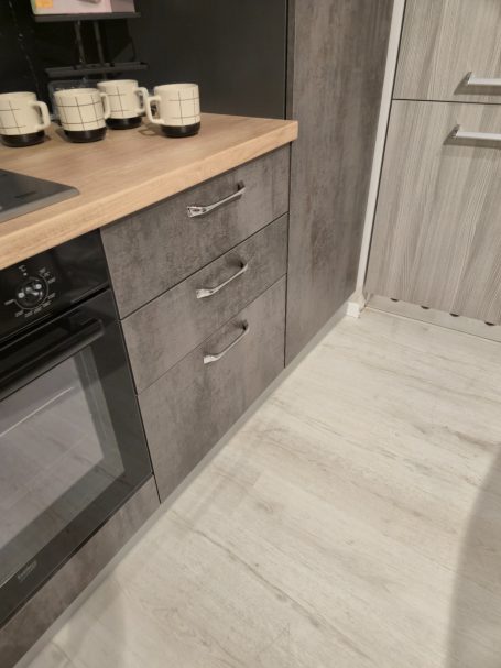 Moderne keuken met een houten werkblad en grijze kasten.