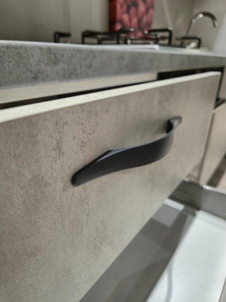 Zwart handvat op een grijze keukenkast met een moderne uitstraling.