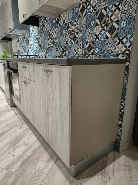 Moderne keuken met een grijze wandkast en een kleurrijke mozaïektegelachtergrond.