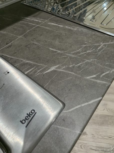 Zwart marmeren aanrechtblad met een RVS gootsteen en het logo van Beko.