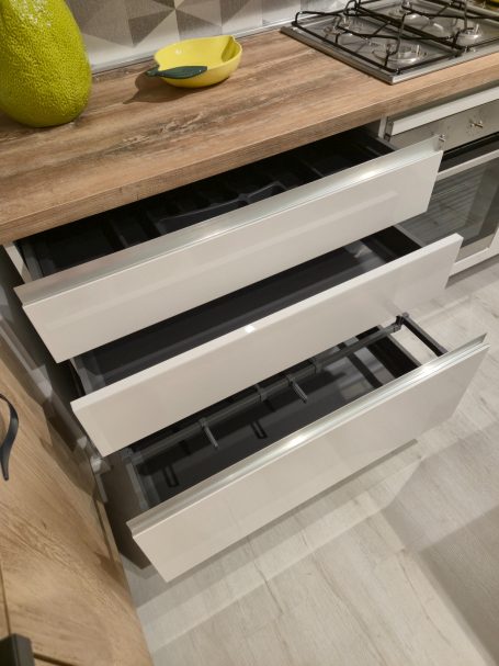 Pure elegantie in Italiaans design Drie open lades in een moderne keuken, met een houten bovenblad en een gasfornuis.