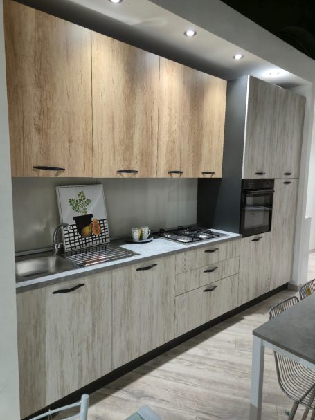 Moderne keuken met houten kasten, kookplaat en oven, stijlvolle verlichting boven.