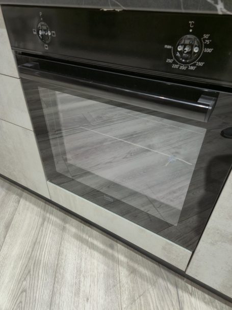 Mira keuken – Moderne rechte keuken met houtlook Moderne oven met een glazen deur, ingebouwd in een keukenmeubel.