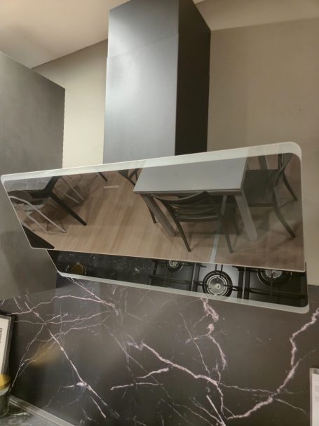 Moderne antracietgrijze keuken Wandafzuigkap met een spiegelachtige afwerking boven een keukenachtergrond.