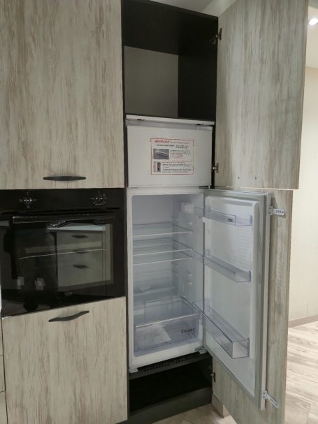 Openstaande koelkast in moderne keuken met licht houten kasten.