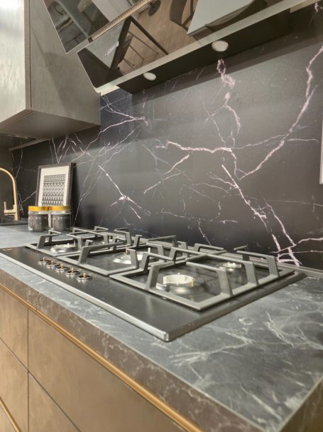 Moderne antracietgrijze keuken Moderne keuken met een gasfornuis en een zwart marmeren achterwand.