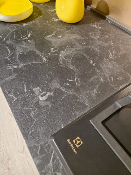 Moderne antracietgrijze keuken Zwarte marmeren aanrecht met gele keukenaccessoires en een kookplaat.