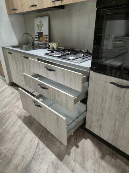 Moderne keuken met houtlook, gasfornuis en open lades.