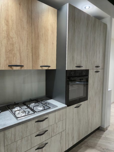 Moderne keuken met houten en grijze kasten, gasfornuis en een inbouwoven.