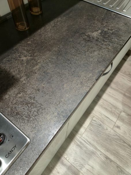Een metalen aanrechtblad met een gestructureerd oppervlak en een kraan aan de zijkant.