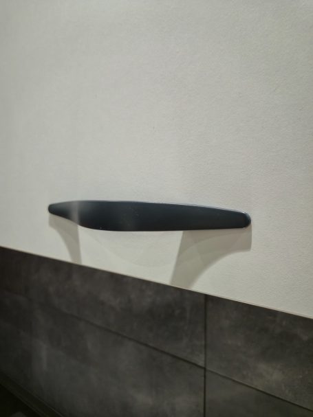 Warme uitstraling, slim ontworpen Zwarte hendel tegen een lichte achtergrond, met een schaduw op de muur.