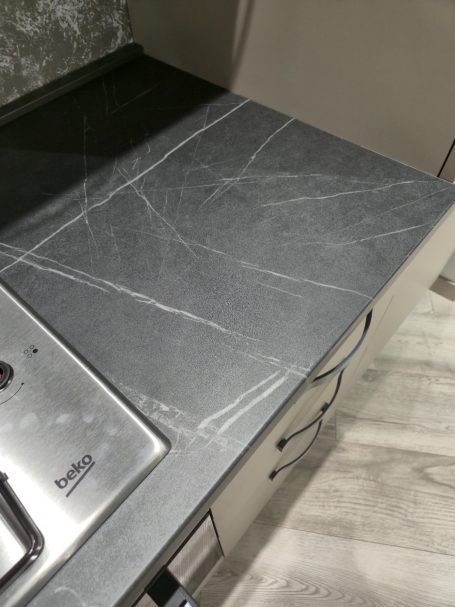 Modern design met een stijlvolle twist Gladde, donkere marmeren aanrecht met lichte aders en een inductiekookplaat.