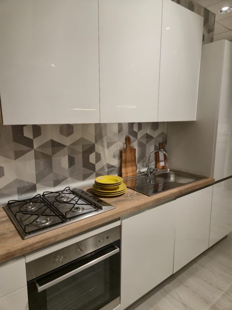 Pure elegantie in Italiaans design Moderne keuken met witte kasten, een houtkleurig aanrecht en geometrische wandtegels.