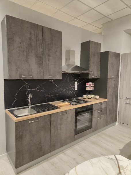 Moderne keuken met grijze kasten, houten werkblad en zwarte backsplash.