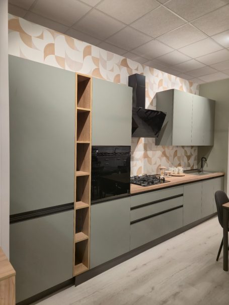 Moderne matgroene keuken Moderne keuken met groene kasten en een houten blad, voorzien van een kookplaat en afzuigkap.