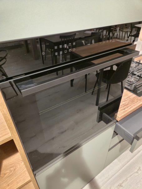 Moderne matgroene keuken Zwarte oven met glazen deur, geïntegreerd in een moderne keuken.