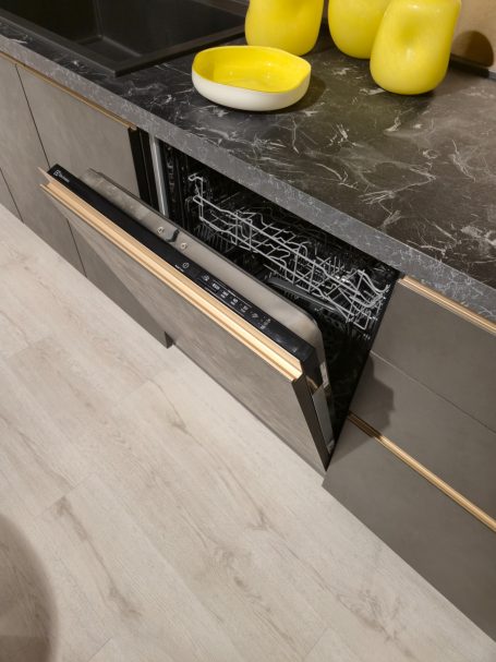 Moderne antracietgrijze keuken Een open vaatwasser in een moderne keuken met een zwart-granieten aanrecht.