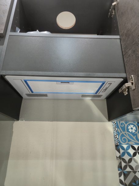 Mira keuken – Moderne rechte keuken met houtlook Een zwart kastje met een open lade en een document met blauwe rand erin.