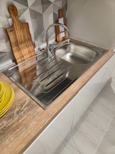 Pure elegantie in Italiaans design RVS spoelbak met houten snijplanken en gele borden op een aanrechtblad.