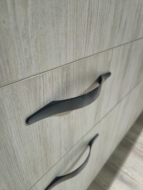 Licht houten kast met een zwart metalen handvat op een lade.