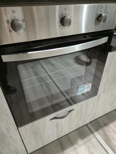Moderne oven met een glazen deur en metalen handgreep, geïntegreerd in een keukenkast.