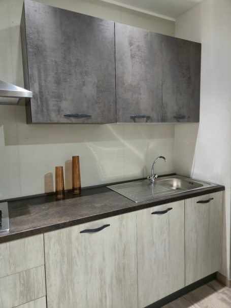 Moderne keuken met een stenen aanrecht, metalen kastjes en houten accessoires.
