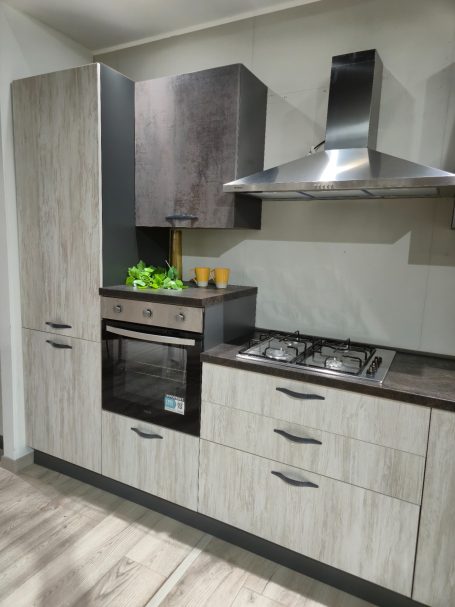 Moderne keuken met grijze kasten, oven en gasfornuis, en groene planten als decoratie.