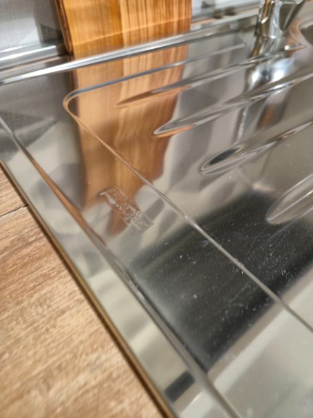 Pure elegantie in Italiaans design Glanzend RVS aanrechtblad met houten snijplank en lichte houten ondergrond.